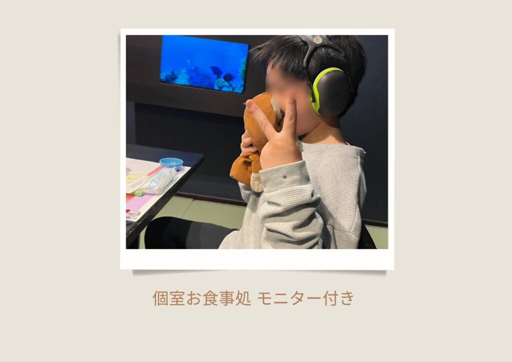 温泉宿「花の丸」のモニター付き個室で、ぬいぐるみを抱えて静かに食事を楽しむ重度自閉症の男の子。A boy with severe autism quietly enjoying a meal in a private dining room with a monitor at Hanano-Maru hot spring inn.