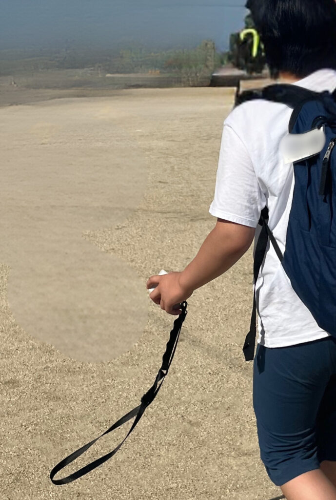 片手に首掛けカードスケジュールを握りしめたイヤマフをつけた自閉症の男の子。